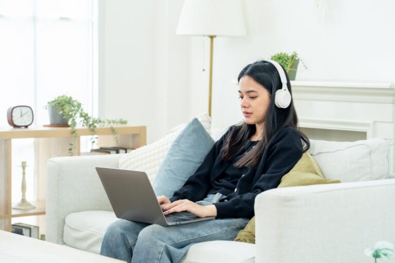 Woman wearing headphones on a private video consultation from her sofa