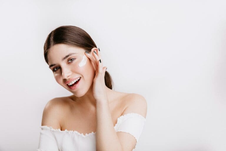 Smiling woman touching her face, with a dab of cream on her cheek