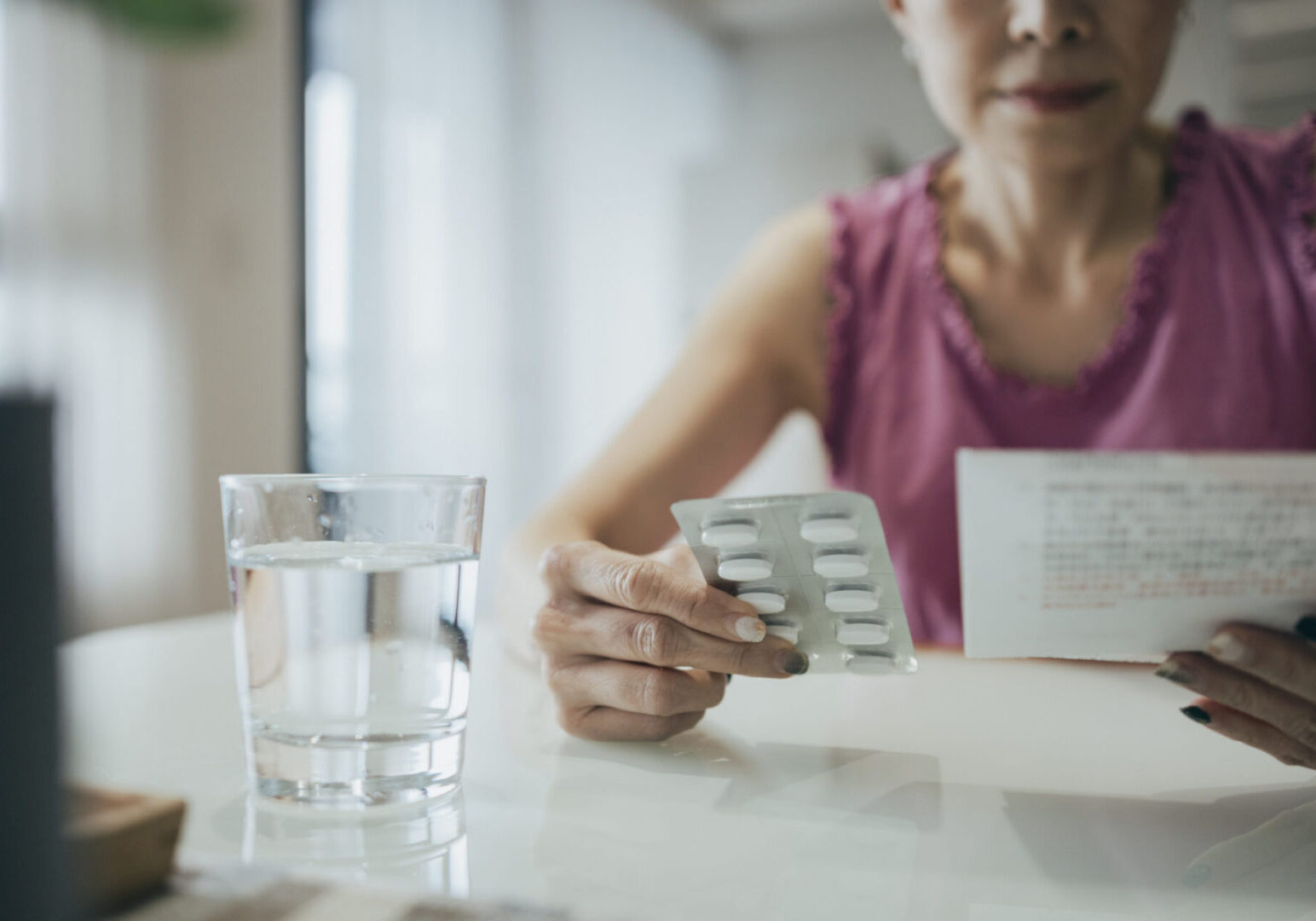 Woman holding medication and reading instructions.